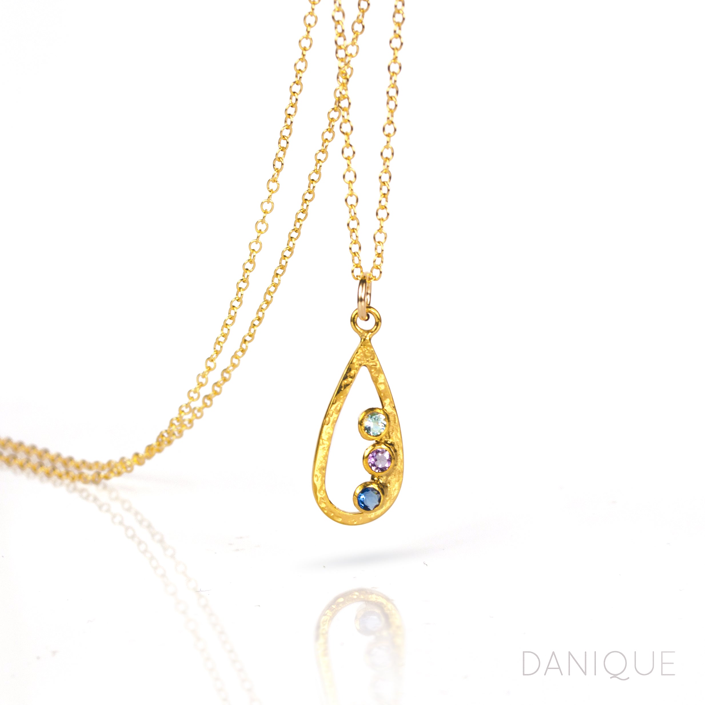 Single gold filled teardrop frame necklace with three 3mm birthstones including blue topaz, purple amethyst, and kyanite. 