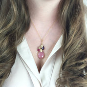 Model in white top is wearing a gold filled mothers necklace with large pink chalcedony birthstone and ruby and onyx kids birthstones with hand stamped leaf charms