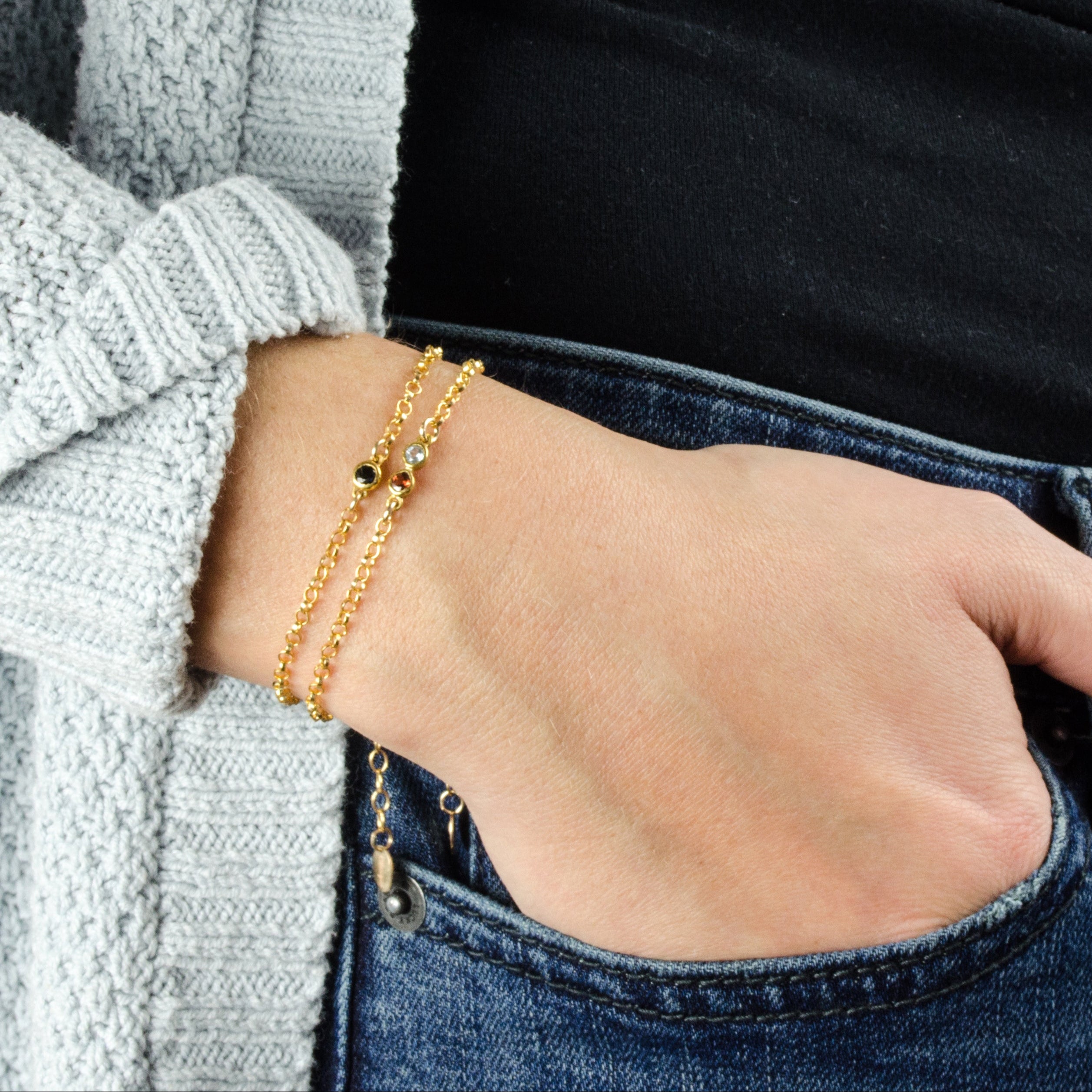 A person in a black shirt and has a hand in her pocket and wears two minimalist natural birthstone bracelets. These bracelets are perfect as Mothers Day gifts, birthstones representing mom and her children, or as single-stone accents for your outfit.