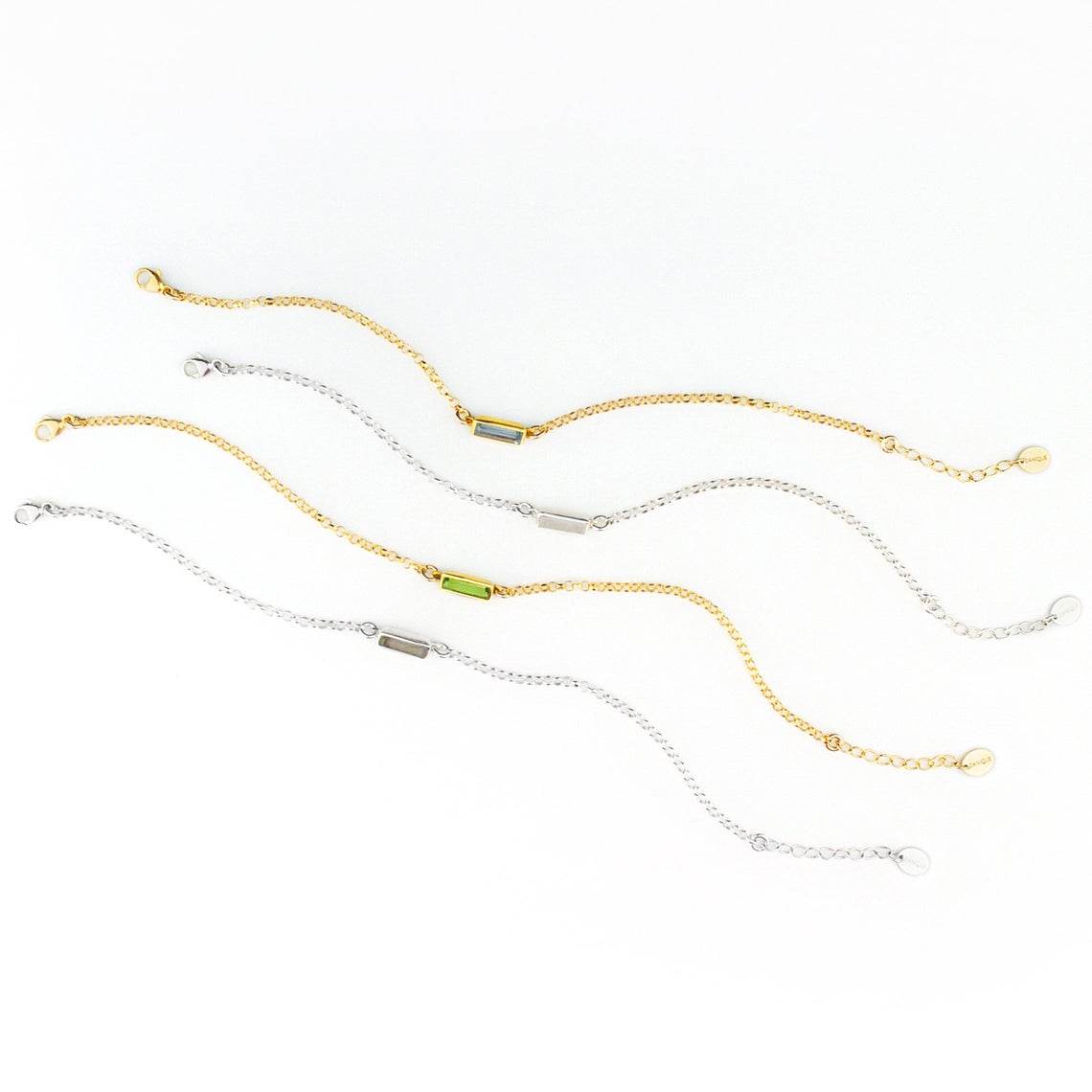 Four alternating gold filled and sterling silver chain adira bar bracelets featuring green onyx, moonstone, peridot and labradorite birthstones on white background