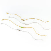 Four alternating gold filled and sterling silver chain adira bar bracelets featuring green onyx, moonstone, peridot and labradorite birthstones on white background