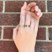 2 hands wear an aqua chalcedony and a kyanite bow tie ring. Adjustable bow tie ring, double triangle birthstone ring, personalized gemstone ring, custom triangle ring, sterling silver birthstone ring, gold adjustable ring, rose gold bow tie ring, unique triangle-cut gemstone, mix-and-match birthstone jewelry, bespoke bow tie ring, customizable gemstone ring, adjustable triangle band, elegant birthstone jewelry, trendy bow tie design, unique gemstone ring, custom birthstone gift, personalized jewelry